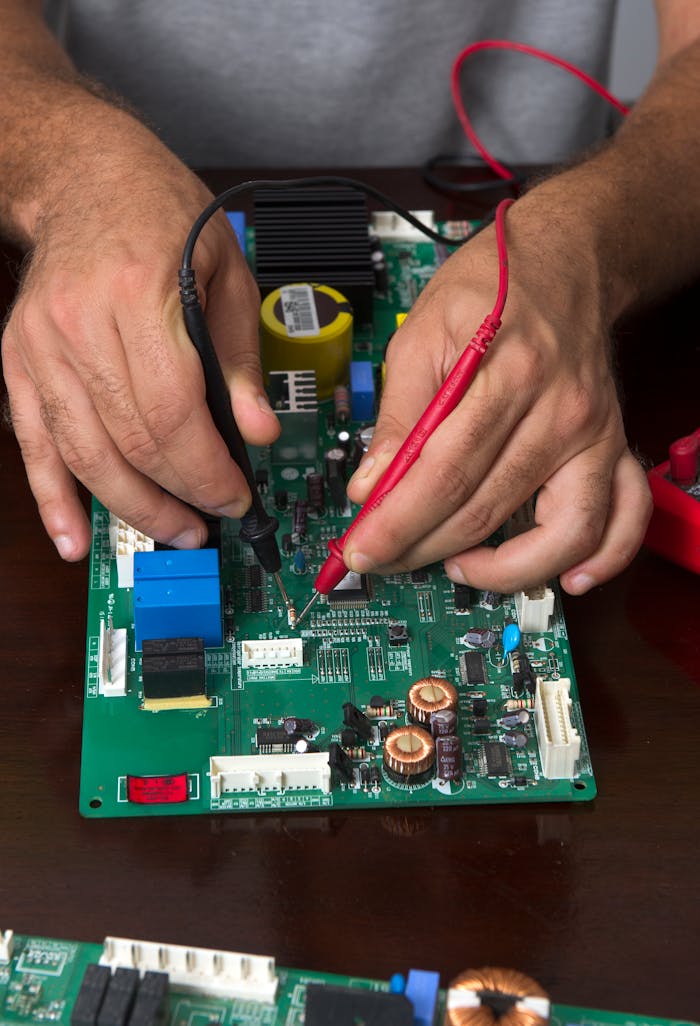 Close-up of hands using probes to test a circuit board during electronic repair.
